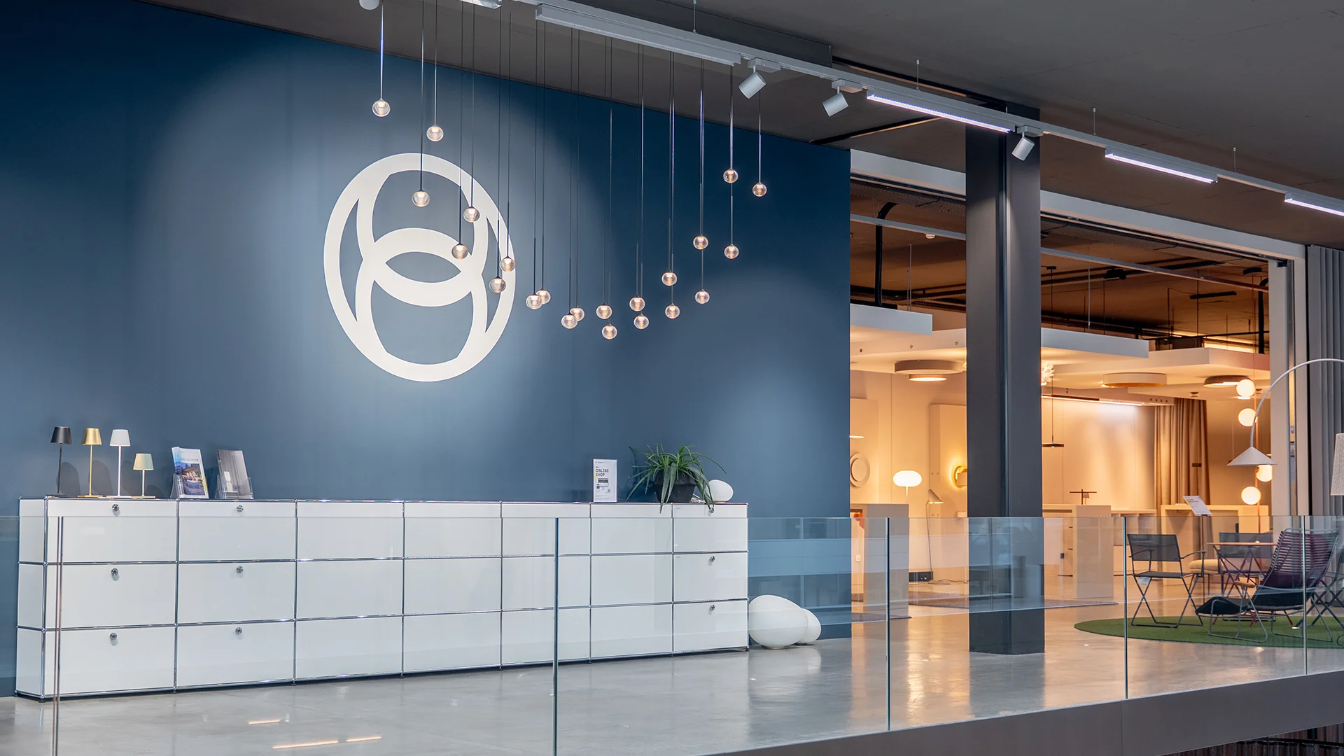 Empfangstheke vor blauer Wand mit Conceptlicht-Logo – Lichtstudio Weiler, Conceptlicht
