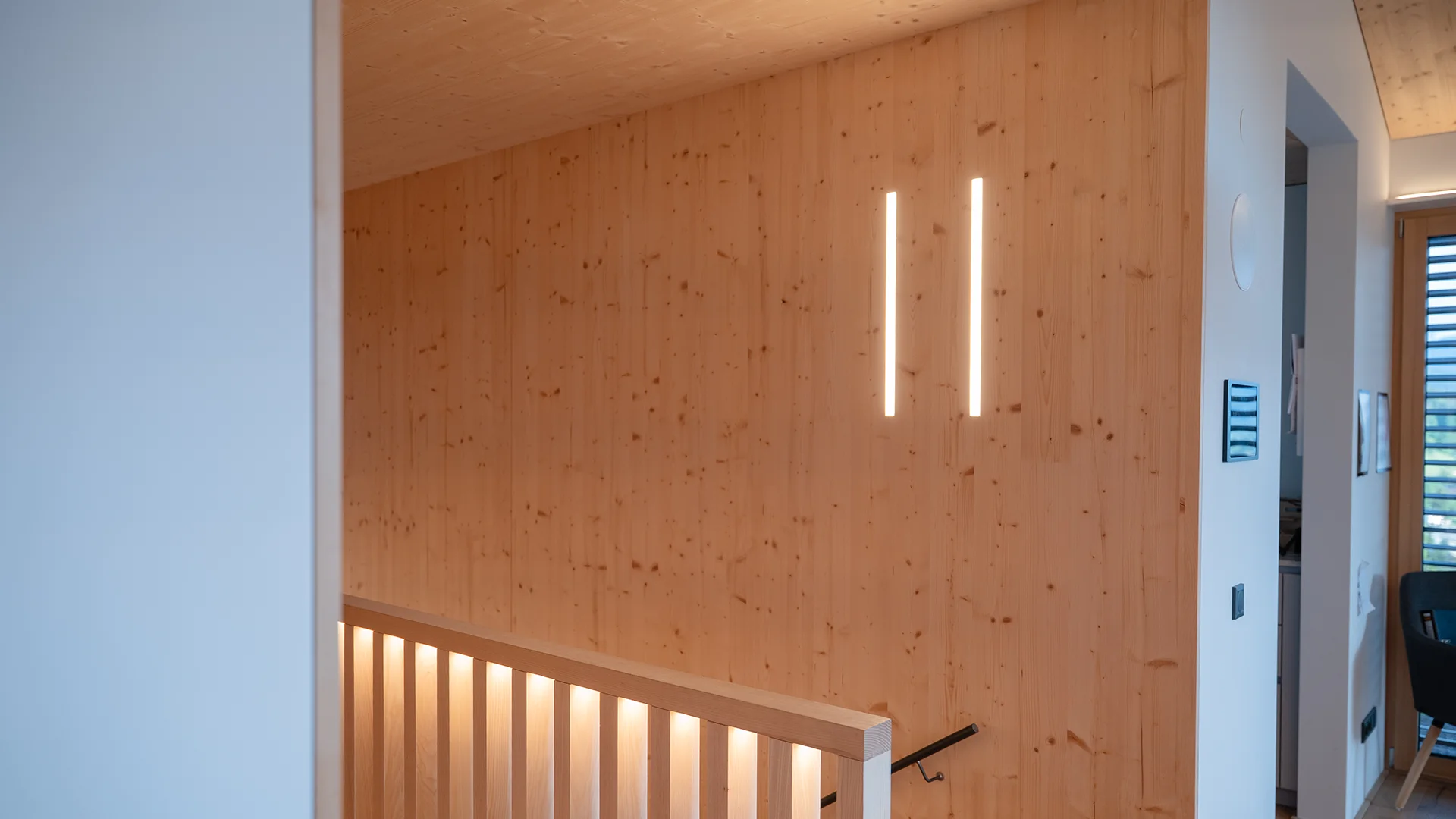 Holzwand mit zwei senkrechten Lichtlinien im Flur – Holzhaus im Rheintal, Conceptlicht