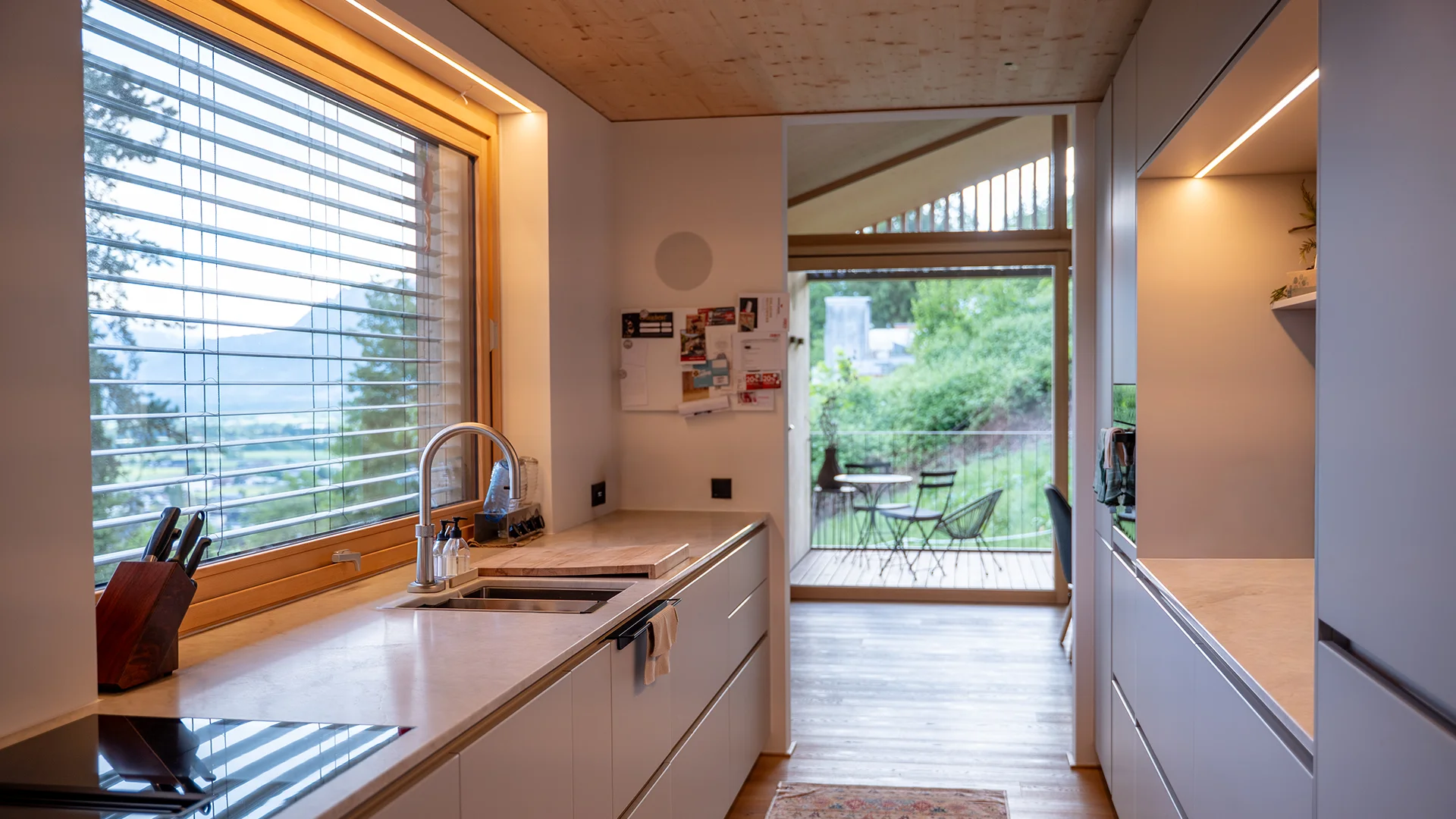 Küchenzeile mit Arbeitsplatzbeleuchtung und Blick auf die Terrasse – Holzhaus im Rheintal, Conceptlicht