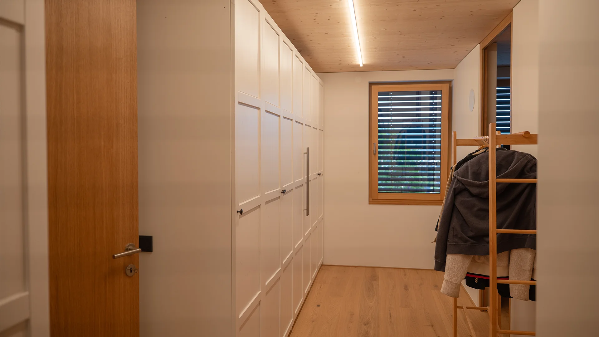 Garderobe mit Einbauschrank und durchlaufender Deckenlichtlinie – Holzhaus im Rheintal, Conceptlicht