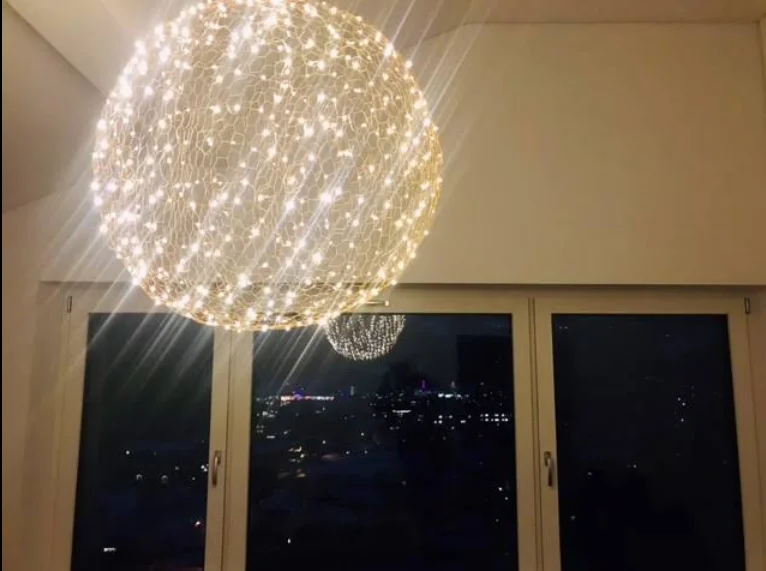 Leuchtende Drahtkugel als Pendelleuchte vor einem Fenster mit nächtlichem Ausblick – Kundenprojekt, Conceptlicht