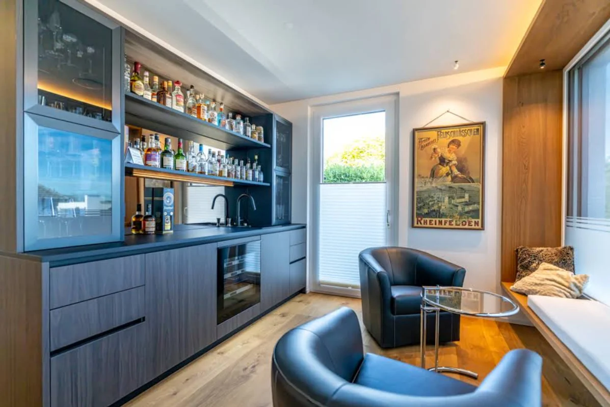 Barbereich mit beleuchteten Regalböden, Sesseln und Fensterbank – Neubau, Conceptlicht